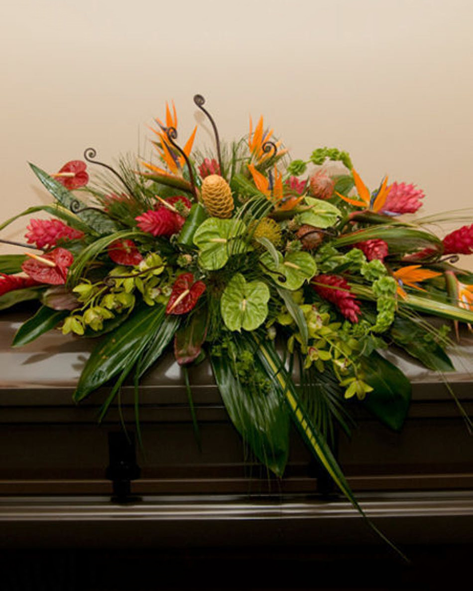 Tropical Remembrance Half Casket Spray-Standard The beauties of the tropics will help to make this casket spray one that will be remembered and appreciated. Dripping with birds of paradise, fresh ginger, red and green anthirium, pin cushion protea and beautiful orchids, Tropical Remembrance will help you make a memorable and caring statement of appreciation.
DELIVERY: Every order is hand-delivered direct to the recipient. These items will be delivered by us locally, or a qualified retail local florist.