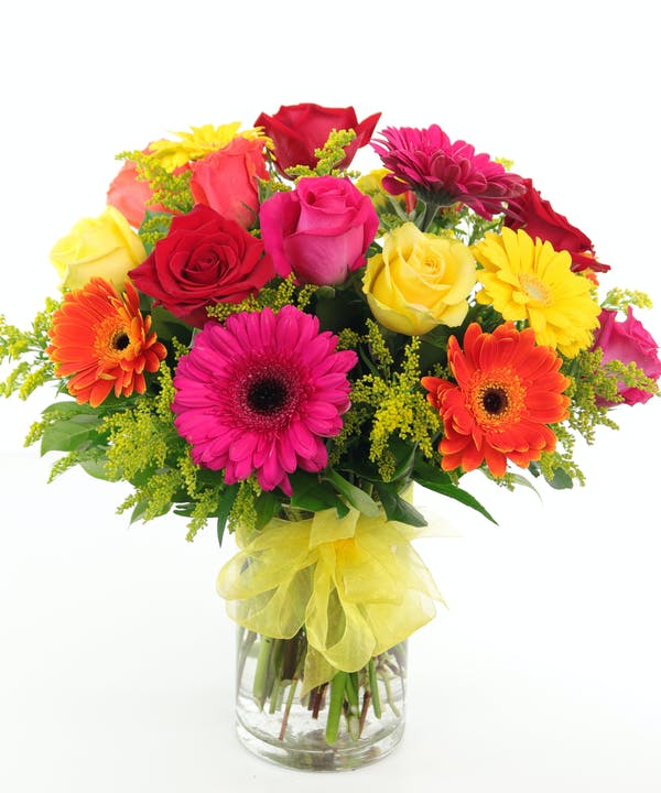 Roses And Gerberas Deluxe - 18 Stems Roses and Gerberas are a beautiful and colorful way to brighten someone's day. Assorted roses and gerbera daisies in brilliant hues create a gorgeous arrangement accented with yellow solidago and assorted greens. Designed in a chic glass vase, this arrangement is a sweet way to light up their life. 
DELIVERY: Every order is hand-delivered direct to the recipient. These items will be delivered by us locally, or a qualified retail local florist.

