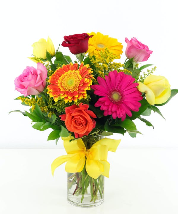 Roses And Gerberas Standard - 9 Stems Roses and Gerberas are a beautiful and colorful way to brighten someone's day. Assorted roses and gerbera daisies in brilliant hues create a gorgeous arrangement accented with yellow solidago and assorted greens. Designed in a chic glass vase, this arrangement is a sweet way to light up their life. 
DELIVERY: Every order is hand-delivered direct to the recipient. These items will be delivered by us locally, or a qualified retail local florist.

