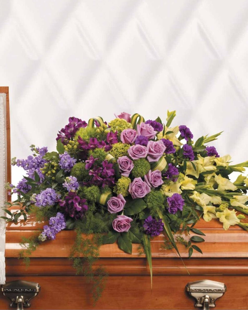 Reflections of Gratitude Casket Spray Half Casket Spray-Standard For a life that has been joyfully lived, this opulent arrangement featuring lavender roses and green gladioli is an expression of gratitude for shared times together. The lush arrangement includes green miniature hydrangea, lavender roses, purple alstroemeria, green gladioli, green trick dianthus, purple carnations, lavender stock and green hypericum, accented with assorted greenery. Approximately 47