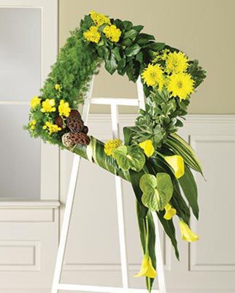 Four Square- Assorted Exotic and Tropical Greens dominate its structure. Anthuriums, Calla Lilies,Gerbera Daisies, Hydrangea, and Lotus Pods accentuate the green base.-Sympathy Wreath