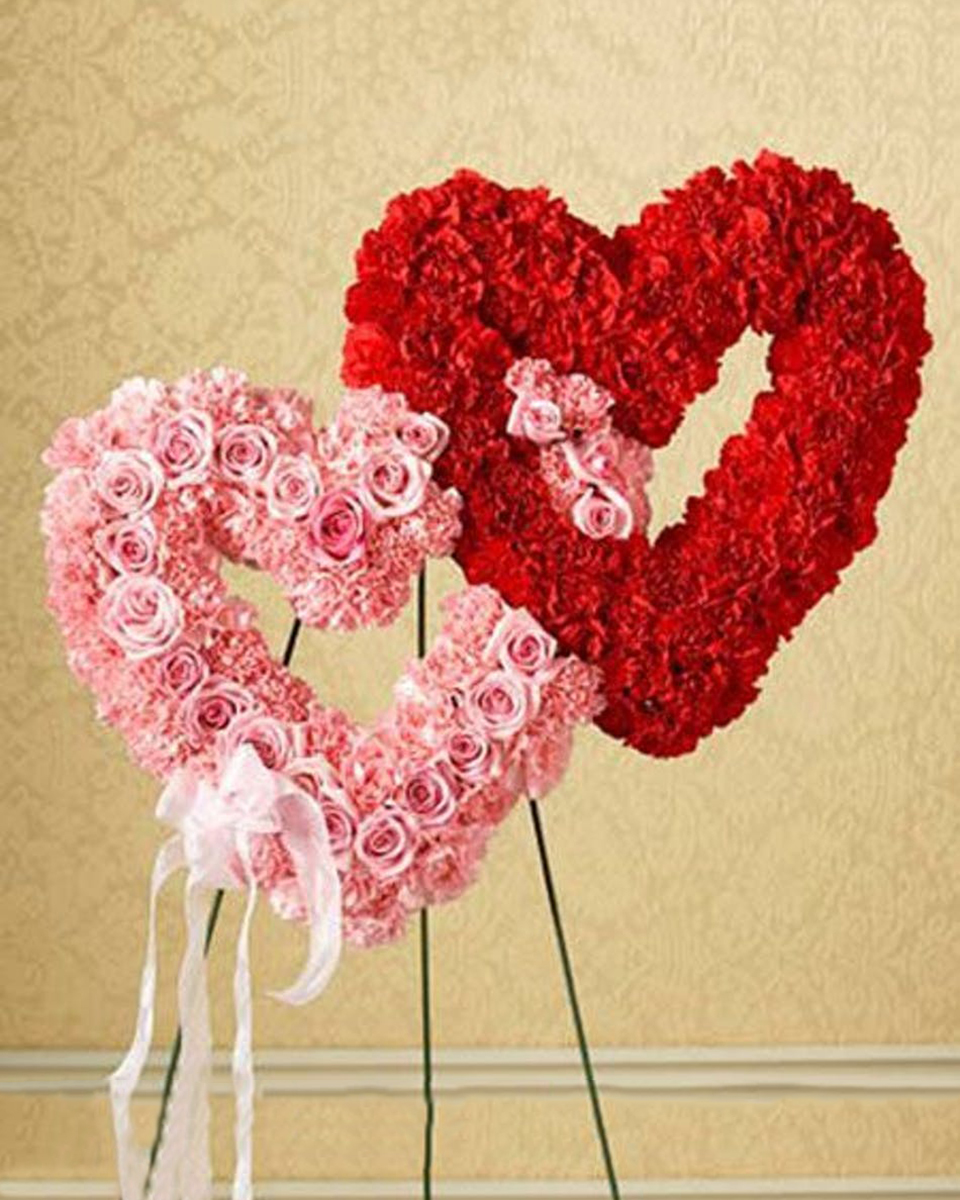Duo Heart Standing Wreath Duo Heart Standing Wreath This open heart standing spray is a perfect symbol of sympathy and support.Two dozen beautiful garden roses and over 100 carnations create an open Double Heart, finished with a pink wired ribbon.
DELIVERY: Every order is hand-delivered direct to the recipient. These items will be delivered by us locally, or a qualified retail local florist.