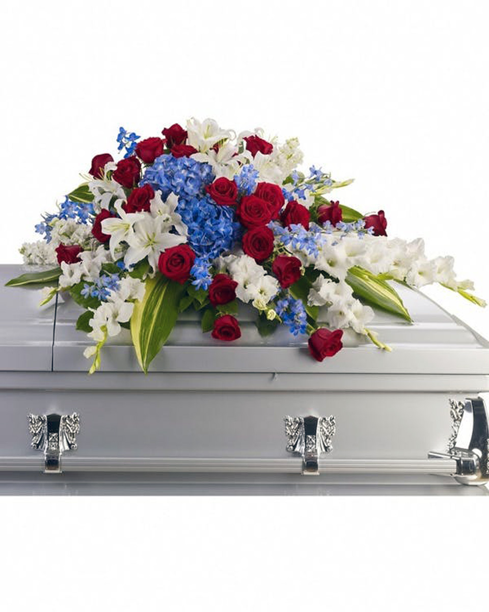 The Patriot Casket Spray Half Casket Spray-Standard Brilliant flowers such as blue hydrangea, red roses, white oriental lilies and much more create this dignified way to honor the deceased. Approximately 46 1/2
