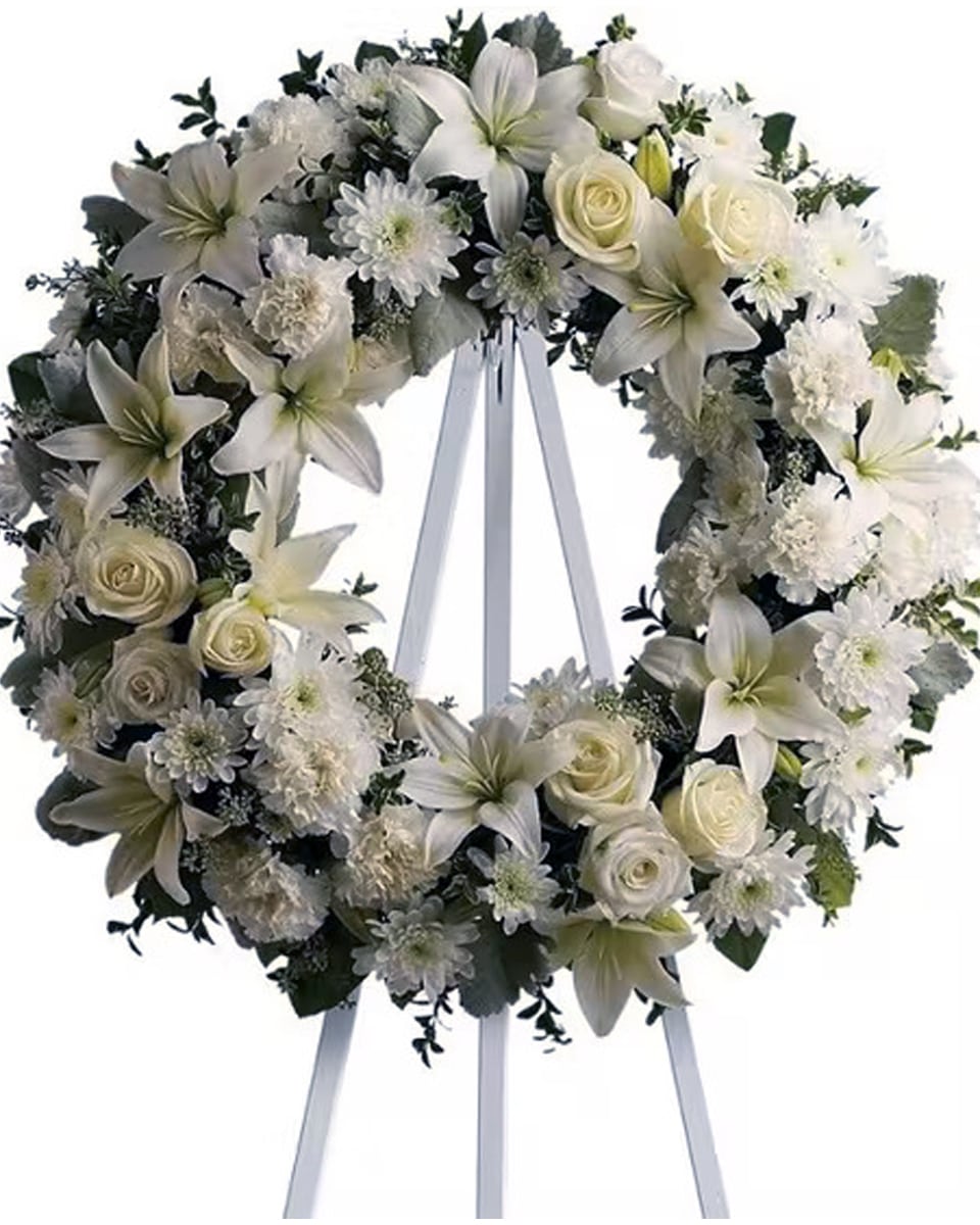 Serenity White Wreath Standard (18 Inch) A ring of fragrant, bright white blossoms will create a serene display at any funeral or wake. This classic wreath is delivered on an easel, and is a thoughtful expression of sympathy and admiration.Arrangement Details:A standing wreath created from fresh white flowers such as roses, Asiatic lilies, carnations and cushion spray chrysanthemums – accented with greenery – is delivered on an easel.
DELIVERY: Every order is hand-delivered direct to the recipient. These items will be delivered by us locally, or a qualified retail local florist.